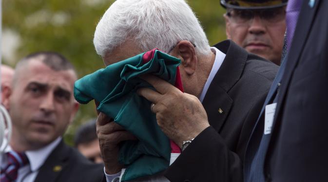 Presiden Palestina Mahmoud Abbas mencium haru bendera negaranya sebelum dikibarkan di markas PBB New York, AS. (Reuters)