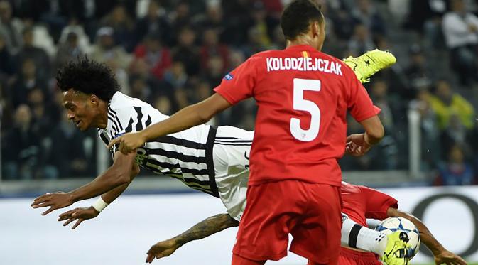 Pemain Juventus, Juan Cuadrado terjatuh saat berebut bola dengan pemain Sevilla pada laga Liga Champions di Stadion Juventus, Italia, Kamis (1/10/2015). (AFP Photo/Olivier Morin)