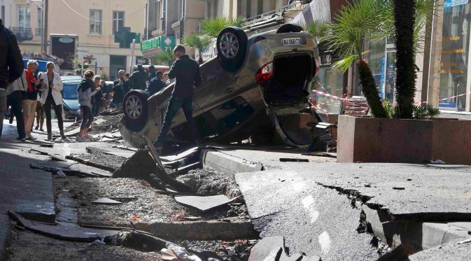 Warga melihat mobil yang terbalik dan jalanan yang hancur akibat banjir di Cannes, Prancis, Minggu (4/10/2015). Akibat peristiwa itu, sebanyak 16 warga dilaporkan tewas. (REUTERS/Eric Gaillard) 