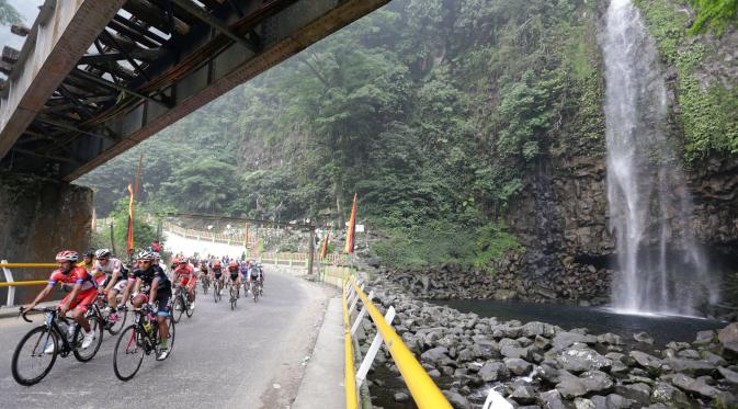 Para pebalap sedang melewati air terjun Lembah Anai dalam Etape 6 Tour de Singkarak 2015 antara Bukittinggi-Batusangkar, Kamis (8/10/2015). (Bola.com/Arief Bagus)