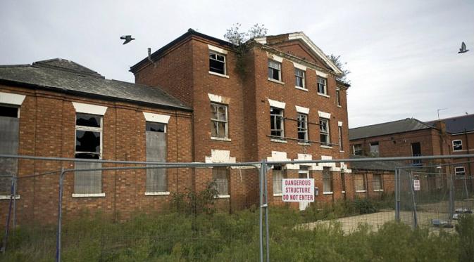 Bangunan rumah sakit St Edmund's dikelilingi oleh pagar besi dengan tanda larangan masuk.
