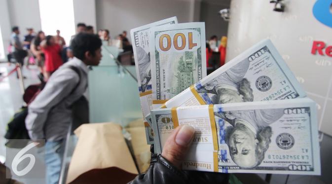 Pengunjung memperlihatkan uang pecahan US$100 di Jakarta, Jumat (9/10/2015). Nilai tukar rupiah terhadap dolar AS pada perdagangan akhir pekan ini, Jumat (9/10/2015) mengalami penguatan, bahkan bergerak ke level Rp 13.400. (Liputan6.com/Angga Yuniar)