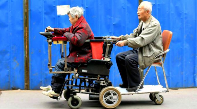 Seorang kakek melakukan modifikasi kursi roda istrinya yang menderita rematik agar mereka bisa selalu bersama. (Sumber CCTV via Shanghaiist)
