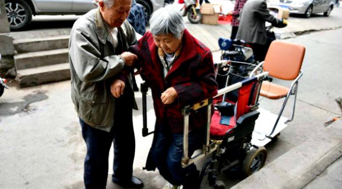 Seorang kakek melakukan modifikasi kursi roda istrinya yang menderita rematik agar mereka bisa selalu bersama. (Sumber CCTV via Shanghaiist)
