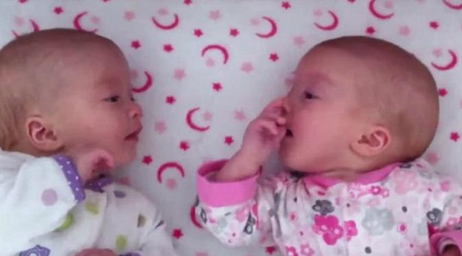 bayi kembar identik menggemaskan terlibat dalam sebuah percakapan yang seru