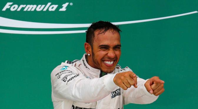 Pembalap Mercedes, Lewis Hamilton merayakan kemenangan usai merebut gelar Grand Prix F1 di Sirkuit The Americas, Minggu (25/10). Ini merupakan gelar juara dunia ketiga bagi Hamilton setelah sebelumnya diraih pada 2008 dan 2014. (REUTERS/Mike Stone)