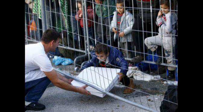 Pelayan membagikan pizza ke anak-anak pengungsi. (foto: Reuters/Leonhard Foeger)