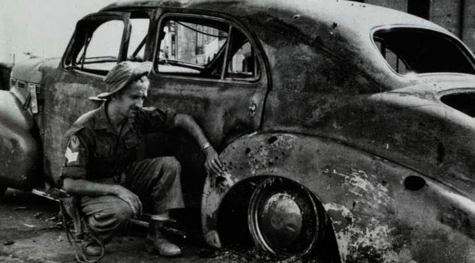 Seorang tentara Inggris memeriksa bangkai mobil Brigjen Mallaby yang tewas pada 30 Oktober 1945 di Surabaya. (Istimewa)