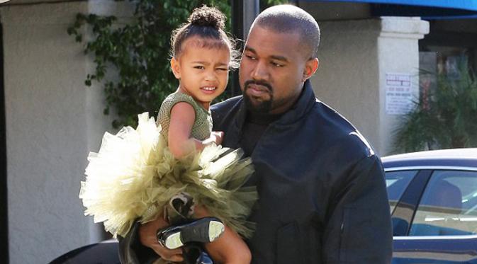 Rapper Kanye West tampak menggendong sang putri, Nort West, saat mengantarkannya ke tempat les balet di Los Angeles, California, Rabu (11/11/2015). (dailymail.co.uk)