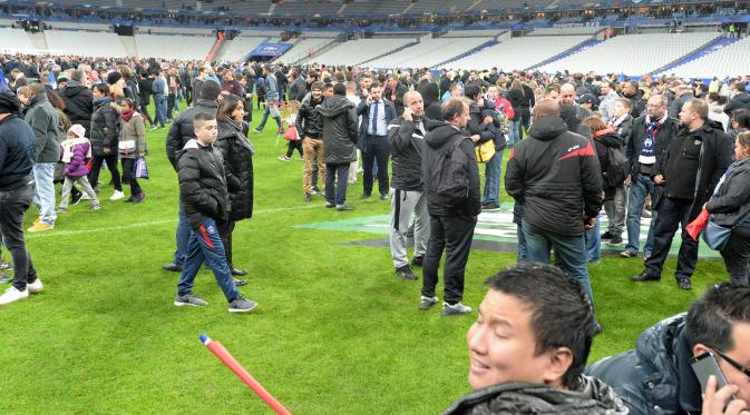 Ribuan Penonton berhamburan di lapangan stadion Stade de France saat menyaksikan pertandingan antara Prancis melawan Jerman di Saint-Denis, Paris, (13/11). Serangan bom terjadi di dekat stadion Stade de France Prancis. (AFP PHOTO/MIGUEL MEDINA)