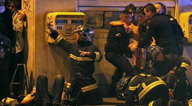 Petugas pemadam kebakaran menolong korban serangan di dekat Gedung Konser Bataclan. (Reuters)