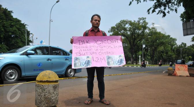 Susanto asal Pandeglang, Banten membawa sebuah karto saat aksi jual ginjal di depan Istana Merdeka, Jakarta, Jumat (20/11). Aksi jual ginjal ke Presiden Jokowi ini untuk biaya operasi anaknya yang disinyalir mencapai Rp.1,2M. (Liputan6.com/Gempur M Surya)