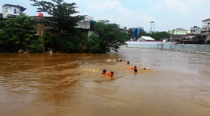 Usai banjir, anak-anak Kampung Pulo sengaja menghanyutkan diri dari jembatan Kampung Melayu hingga Jalan Jatinegara Barat, Jakarta Timur. (Liputan6.com/Ahmad Romadoni)