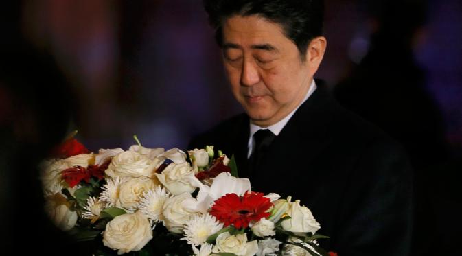 PM Jepang Shinzo Abe membawa karangan bunga tanda bela sungkawa di salah satu lokasi serangan berdarah Paris di gedung konser Bataclan, Prancis, Minggu (30/11). (REUTERS/Gonzalo Fuentes)