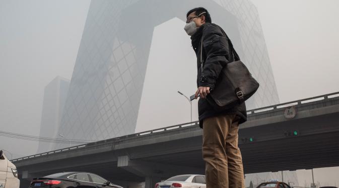 Warga mengenakan masker saat kabut asap menyelimuti Beijing, China, Senin (30/11). Pemerintah setempat mengumumkan keadaan siaga dan menyarankan warga Beijing untuk berada dalam rumah karena kandungan polusi udara yang berbahaya. (AFP PHOTO/ FRED DUFOUR)
