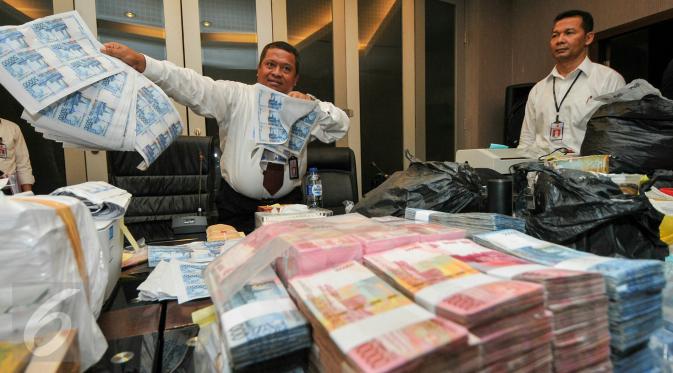 Petugas Bareskrim menunjukan lembaran uang palsu, Jakarta, Senin (7/12/2015 Ratusan lembar uang palsu tersebut diduga akan disebar dalam pilkada serentak (Liputan6.com/Yoppy Renato)