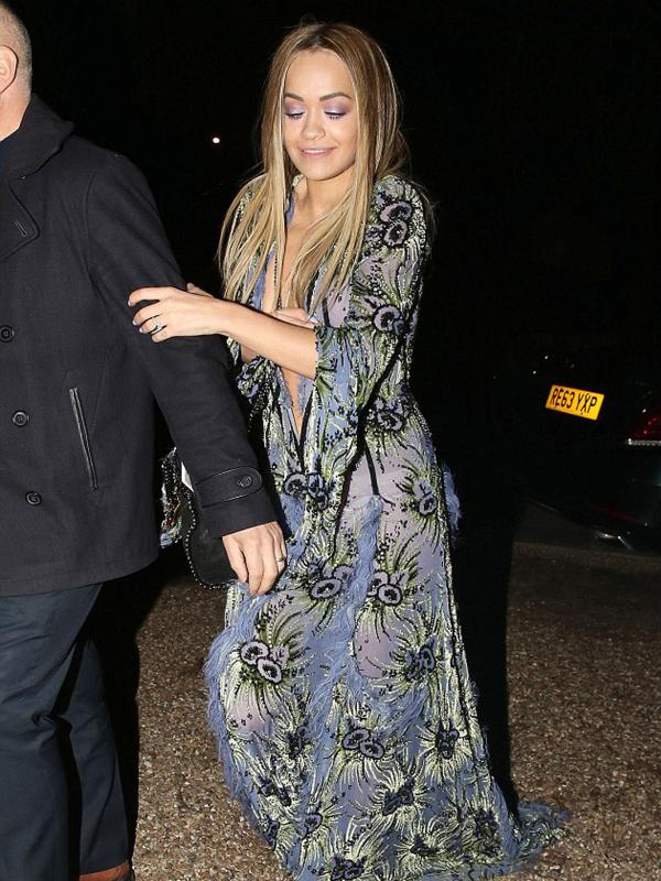 Rita Ora diantar saat akan memasuki mobilnya usai berpesta dengan teman - temannya di london sabtu malam. ia tidak menyadari bahwa gaun yang ia pakai sangat tak beretika dan menampakkan payudaranya secara jelas. (Dailymail.co.uk)