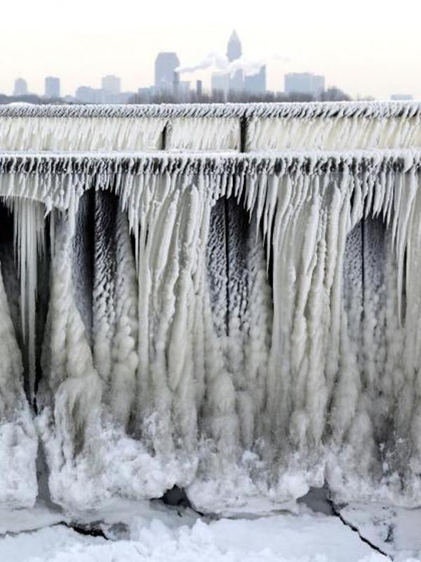 8 Januari 2015. Es dari Danau Erie yang terbentuk pada trotoar jalan dengan latar belakang Cleveland, Ohio. (Via: time.com)