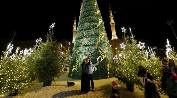 Warga berfoto dengan latar belakang pohon Natal yang dirancang oleh desainer Lebanon, Elie Saab di depan Masjid Al-Amin, di pusat kota Beirut, 12 Desember 2015. (REUTERS/Jamal Saidi)