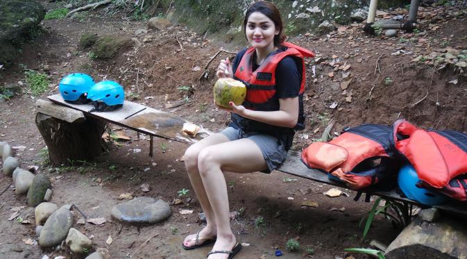 Hilda Vitria Khan menikmati kelapa muda saat jeda arung jeram di Sungai Cicatih, Sukabumi, Sabtu (12/12/2015). (Bola.com/Arief Bagus)