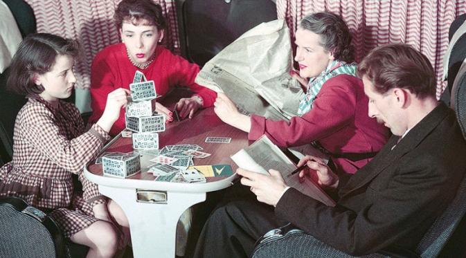 Anak bermain tumpukan kartu, ibu membaca koran, dan ayah menyimak buku dalam penerbangan di masa lalu ( AirlineRatings.com)