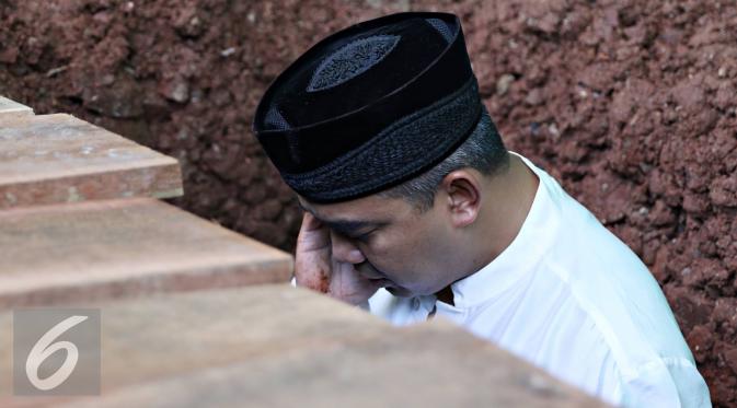 Presenter Farhan saat mengazdani anak pertamanya Muhammad Ridzky Khalid di TPU Tanah Kusir, Jakarta, Senin (21/12). Ridzky menghebuskan nafas terakhirnya di usia 16 tahun pada Minggu, (20/12/2015) pukul 13.40 WIB. (Liputan6.com/Immanuel Antonius)