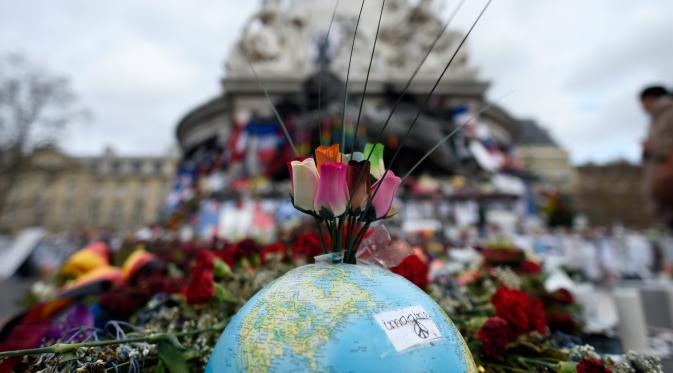 Karangan bunga di atas globe di Place de la Republique, Paris (24/12/2015). Aksi simpatik ini untuk mengenang tragedi serangan Paris yang menewaskan 130 orang. (AFP Photo/Miguel Medina).