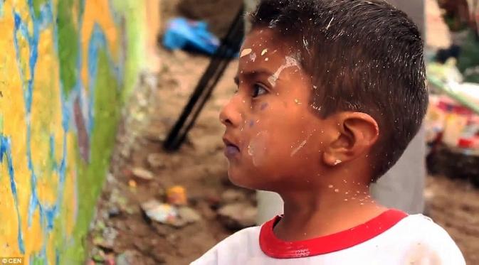 Coretan cat di wajah tak menghalangi anak ini untuk menggambar mural di Wall of Shame, Peru. | via: CEN