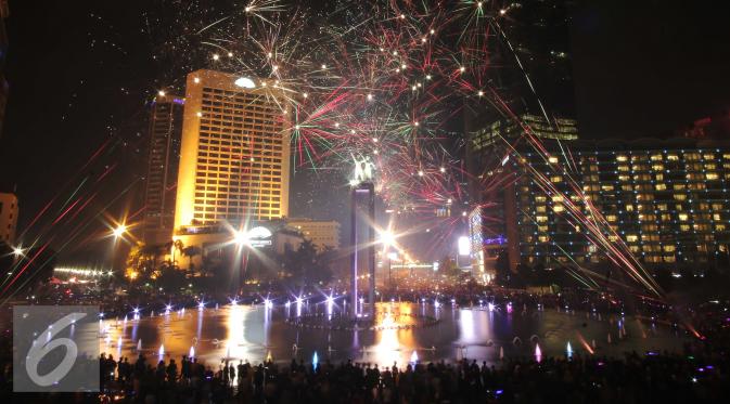 Warga saat menikmati malam tahun baru dengan dengan pertunjukan kembang api di Bundaran HI, Jakarta, Jumat (1/1/2016) malam. Kemeriahan kembang api tersebut merupakan bentuk perayaan pergantian tahun 2015 menuju 2016. (Liputan6.com/Angga Yuniar)