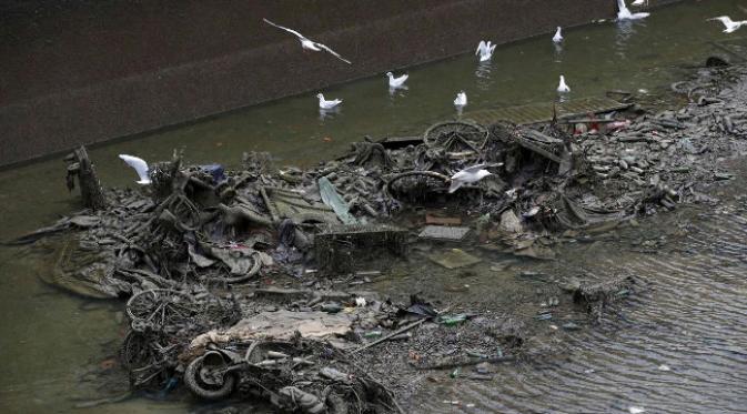 Sepeda dan sepeda motor bekas bertumpuk-tumpuk di dasar kanal. (foto: Reuters)