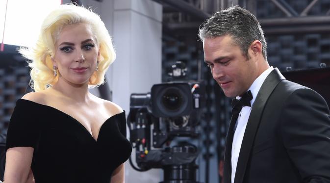 Aktor Taylor Kinney terlihat menggandeng sang tunangan yang juga penyanyi nyentrik, Lady Gaga saat menghadiri ajang penghargaan film tahunan, Golden Globes 2016 di Beverly Hilton Hotel, California, Minggu (10/1). (AFP PHOTO/VALERIE MACONA)