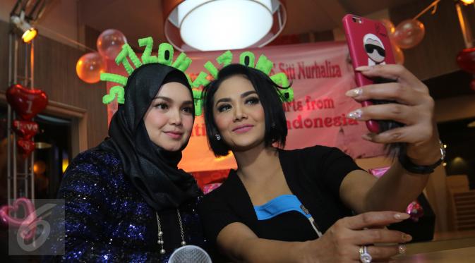 Siti Nurhaliza berfoto bersama Krisdayanti saat merayakan ulang tahun sang Diva asal Malaysia di restoran cepat saji di kawasan Kemang, Jakarta, Minggu (10/1). Pelantun tembang Cindai ini berulang tahun pada 11 Januari. (Liputan6.com/Herman Zakharia)