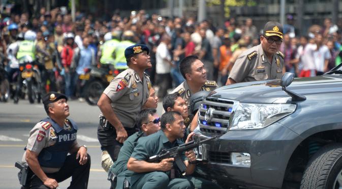 Sejumlah polisi mengambil posisi di dekat sebuah mobil saat melakukan pengejaran terhadap pelaku ledakan di pospol Sarinah, Jakarta, Kamis (14/1). Baku tembak terjadi di depan Sarinah setelah suara ledakan ketiga terjadi.  (AFP PHOTO/Bay Ismoyo)