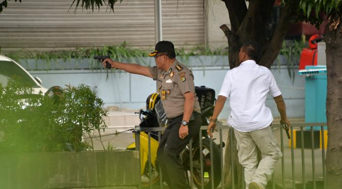 Polisi mengarahkan senjata ke pelaku yang bersembunyi di dalam kafe pasca ledakan di pospol Sarinah, Jakarta, Kamis (14/1). Baku tembak terjadi di depan Sarinah setelah suara ledakan ketiga terjadi.  (AFP PHOTO/Bay Ismoyo)