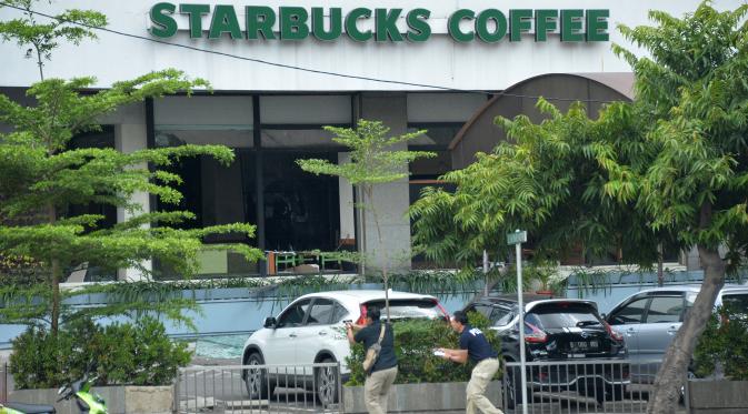Polisi berpakaian preman mengarahkan senjata ke tersangka yang bersembunyi di dalam kafe pasca ledakan di pospol Sarinah, Jakarta, Kamis (14/1). Baku tembak terjadi di depan Sarinah setelah suara ledakan ketiga terjadi. (AFP PHOTO/Bay Ismoyo)