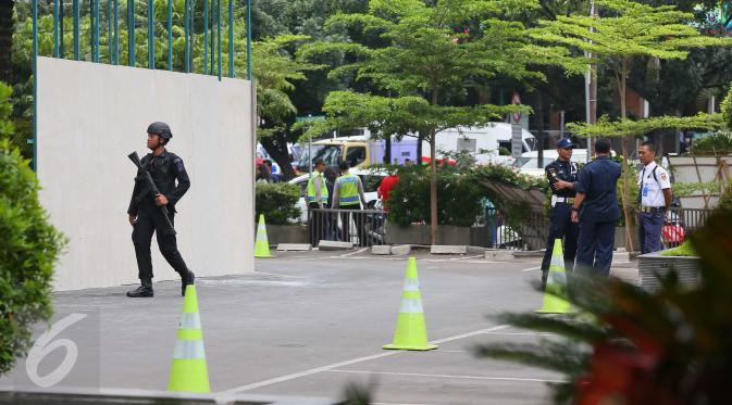 Seorang petugas kepolisian bersenjata terlihat berjaga di sekitar Menara Cakrawala, Jakarta, Sabtu (16/1). Pasca ledakan di Jalan MH Thamrin pada Kamis (14/1) lalu, petugas keamanan menutup rapat pintu masuk gedung tersebut. (Liputan6.com/Faizal Fanani)