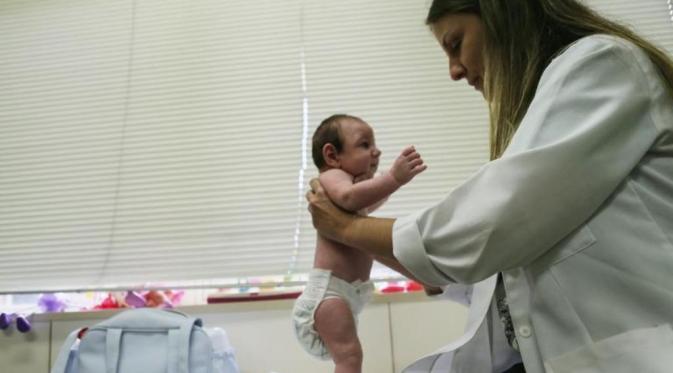Seorang dokter memeriksa bayi di Recife, Brasil. (Via: news.nationalgeographic.com)