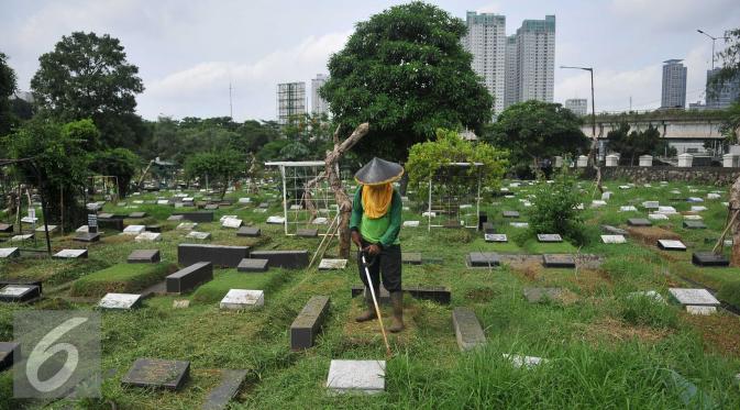 Pekerja membersihkan area makam di TPU Karet Bivak, Jakarta (2/2). Dinas Pertamanan dan Pemakaman telah menerapkan sistem online dalam pelayanan pemakaman di 77 TPU Jakarta. (Liputan6.com/Gempur M Surya)