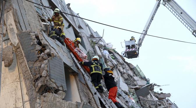 Tim penyelamat mengevakuasi warga yang berada dibangunan yang runtuh akibat 6,4 SR mengguncang Tainan di Taiwan, Sabtu (6/2). Gempa terjadi pukul 4 subuh tadi telah menghancurkan beberapa apartemen di kawasan Wei Guan, Tainan, Taiwan. (REUTERS/Stringer)