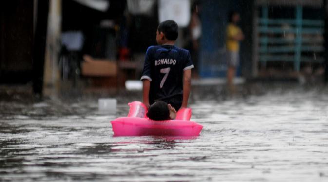 Seorang anak bermain saat banjir menggenangi kawasan Pasar Buncit, Jakarta Selatan, Selasa (9/2/2016). Banjir menggenangi kawasan tersebut hingga setinggi 100 cm akibat luapan Kali Kemang. (Liputan6.com/Gempur M Surya)