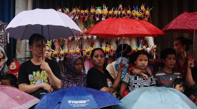 Warga menggunakan payung saat menyaksikan parade Pesta Rakyat Bogor dan perayaan Cap Go Meh di Kota Bogor, Senin (22/2/2016). Ribuan peserta mengikuti parade Pesta Rakyat Bogor 2016 dan pesta perayaan 