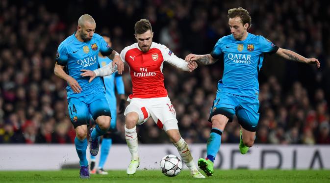 Aaron Ramsey berusaha melewati dua gelandang tangguh Barcelona, Javier Mascherano dan ivan rakitic pada leg pertama 16 besar Liga Champions di Stadion Emirates, Inggris (24/2). Barcelona menang atas Arsenal dengan skor 2-0. (Reuters/Dylan Martinez)