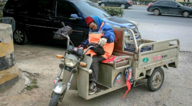 Dalam foto, sang nenek dengan balutan seragam dinas berwarna biru dan orange nampak tengah tertidur pulas. (Shanghaiist.com)
