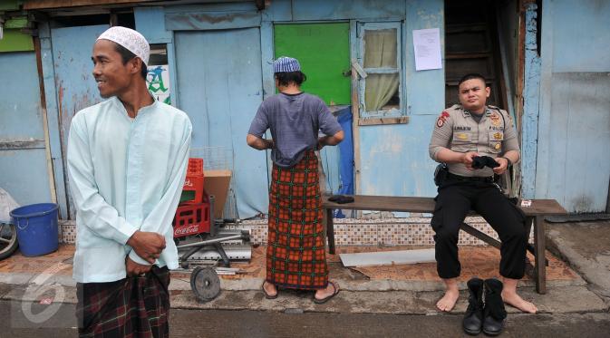 Warga bersama anggota polisi seusai melaksanakan Shalat Jumat di sebuah masjid di kawasan Kalijodo, Jakarta, Jumat (26/2). Shalat Jumat ini merupakan yang terakhir sebelum penertiban kawasan Kalijodo oleh Pemkot DKI. (Liputan6.com/Johan Tallo)