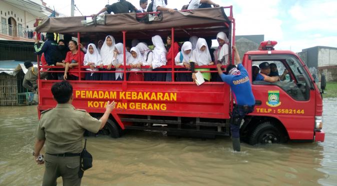 Petugas BNPD dan Pemadam Kebakaran Kota Tangerang bantu para siswa menyeberangi banjir (Liputan6.com/Pramita Tristiawati)