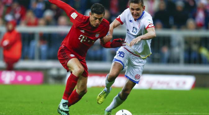 Penyerang Bayern Munchen, Robert Lewandowski (kiri), saat berusaha melewati adangan pemain Mainz 05. Lewandowski bakal menguji ketajaman saat timnya bersua Borussia Dortmund, dini hari nanti, di markas lawan. (Reuters/Michael Dalder)