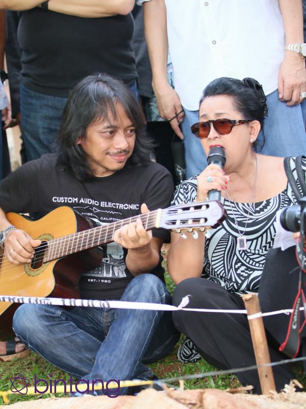 Dewa Budjana memainkan gitar mengiringi nyanyian lagu rohani di pemakaman Ireng Maulana (Adrian Putra/Bintang.com)