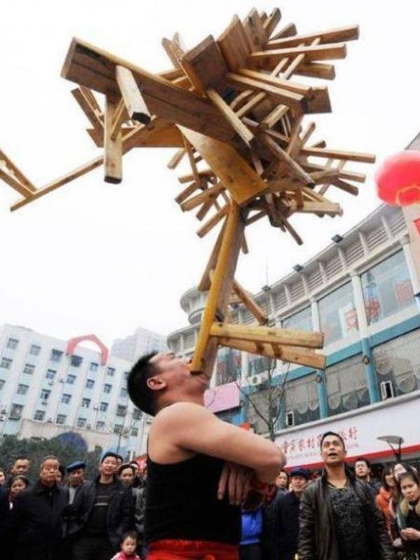 Li Hongxiao berhasil menyeimbangkan 24 bangku seberat 75 kg selama 10 detik hanya dengan menggunakan giginya. (via: People.com)