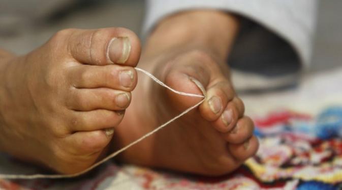 Sejak 21 tahun ia sudah belajar menjahit dengan kakinya. (via: shanghaiist.com)
