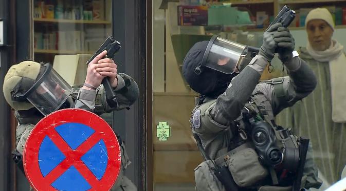 Dua Polisi antiteror Belgia bersenjata saat menggerebek sebuah apartemen di Molenbeek, Brussel, Belgia, (8/3). Wilayah ini memang dihuni oleh imigran-imigran asal Afrika Utara. (REUTERS/VTM)